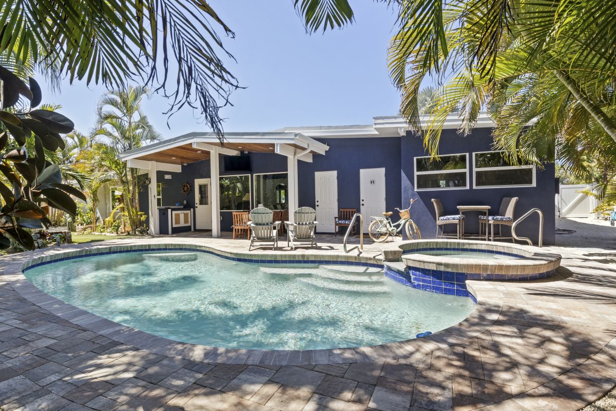 Your private tropical oasis awaits with a sparkling pool and hot tub surrounded by swaying palms and comfortable lounge seating.