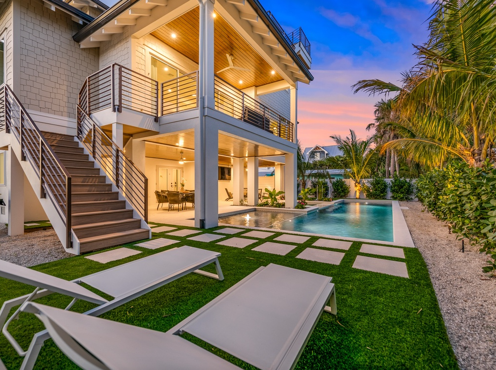 Modern coastal architecture framed by swaying palms and vibrant sunset skies, featuring a pristine pool and tropical landscaping in the surrounding area.