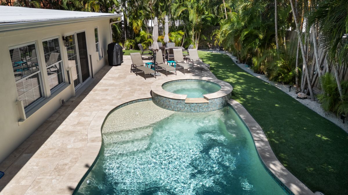Soak up the Florida sunshine in your private backyard paradise, where a shimmering pool with a built-in spa awaits you beneath swaying palms and lush tropical greenery.