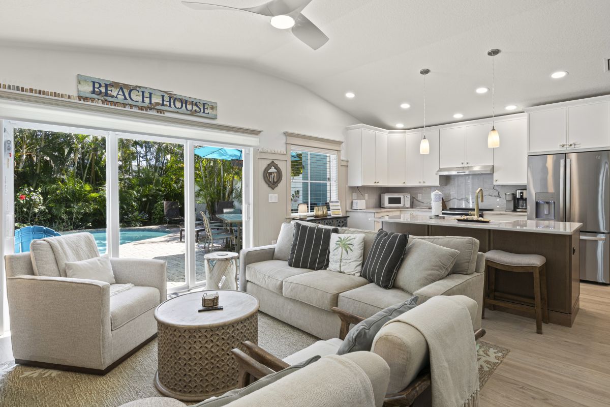 Sink into plush sofas in your open-concept living space, where coastal charm meets modern luxury and pool views beckon through sliding doors.