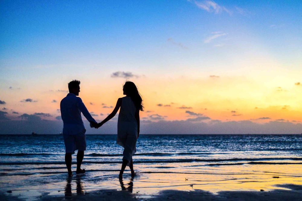 couples on beach holding hands at sunset