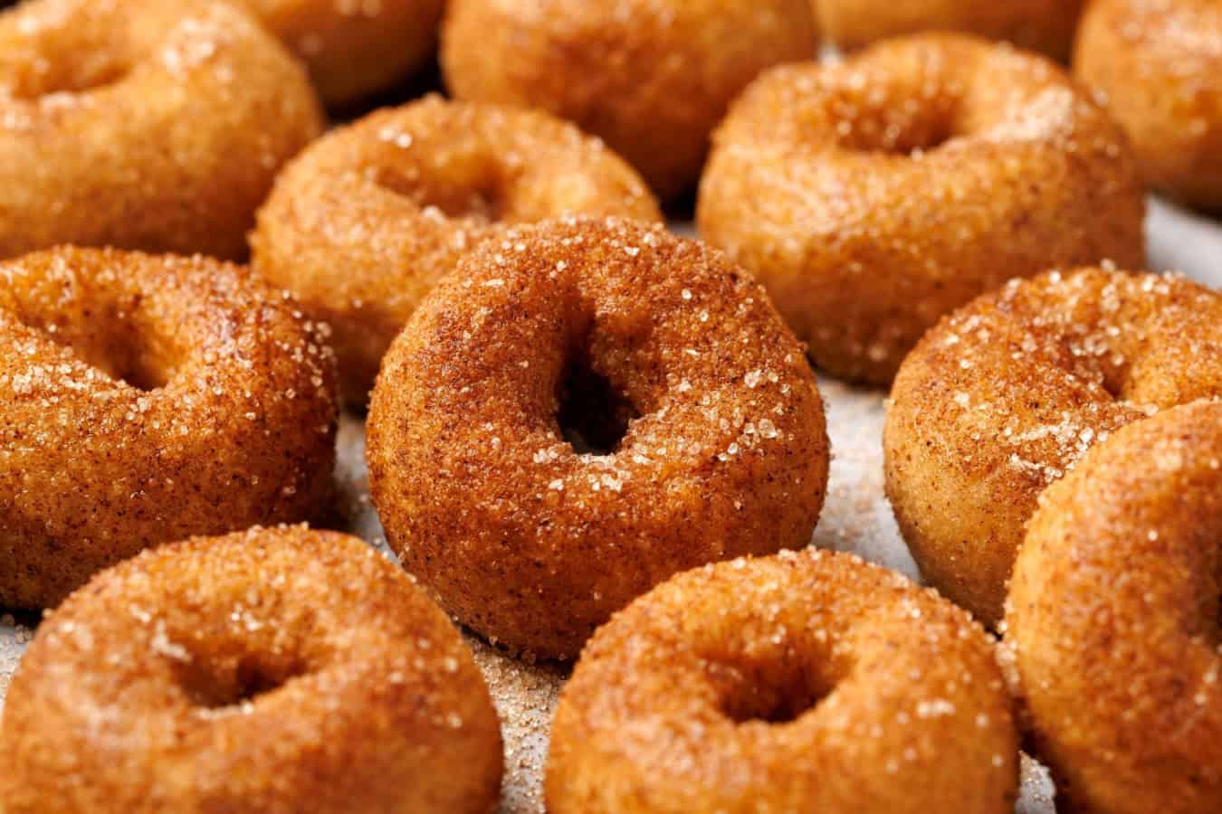 a platter full of small sugared donuts