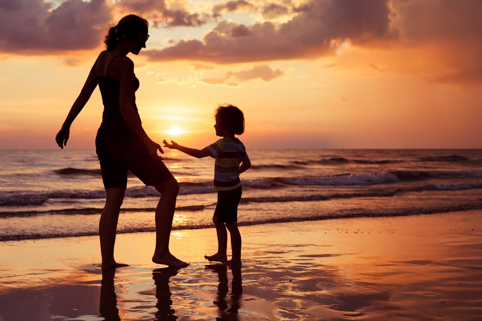 Mom and child on beach during sunrise