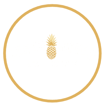 Brand logo for Beach House Real Estate with a gold pineapple graphic inside a circular gold border on a black background, showing the company name.